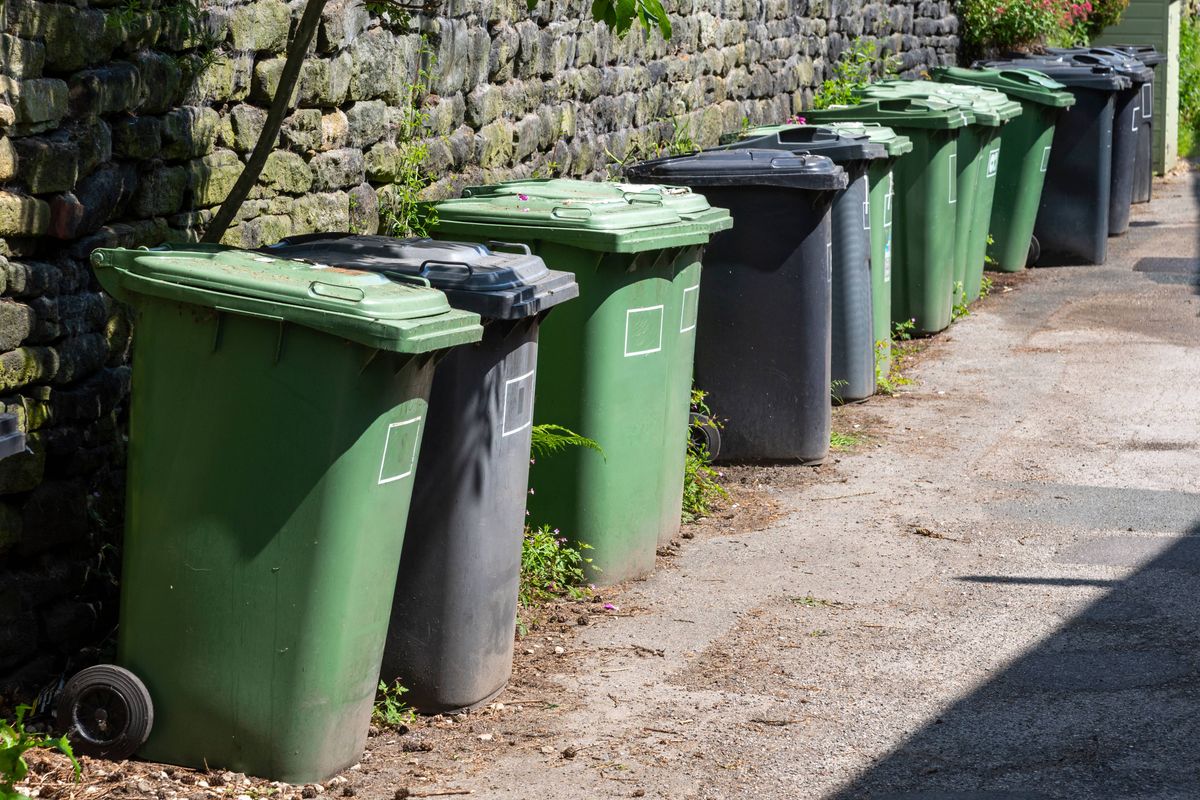 Refuse bins lined up opposite a terrace of cottages in Hinchliffe Mill village near Holmfirth, Northern England.