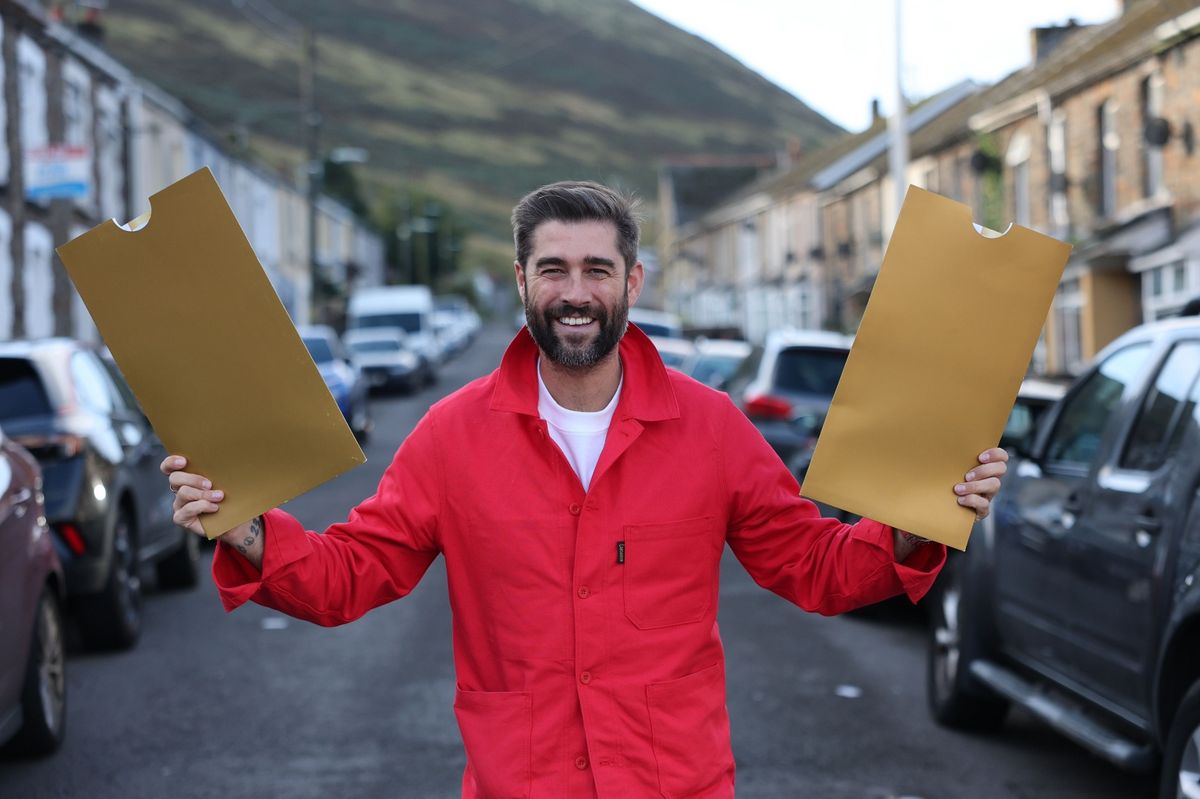 A man stood in the middle of a street holding two envelopes