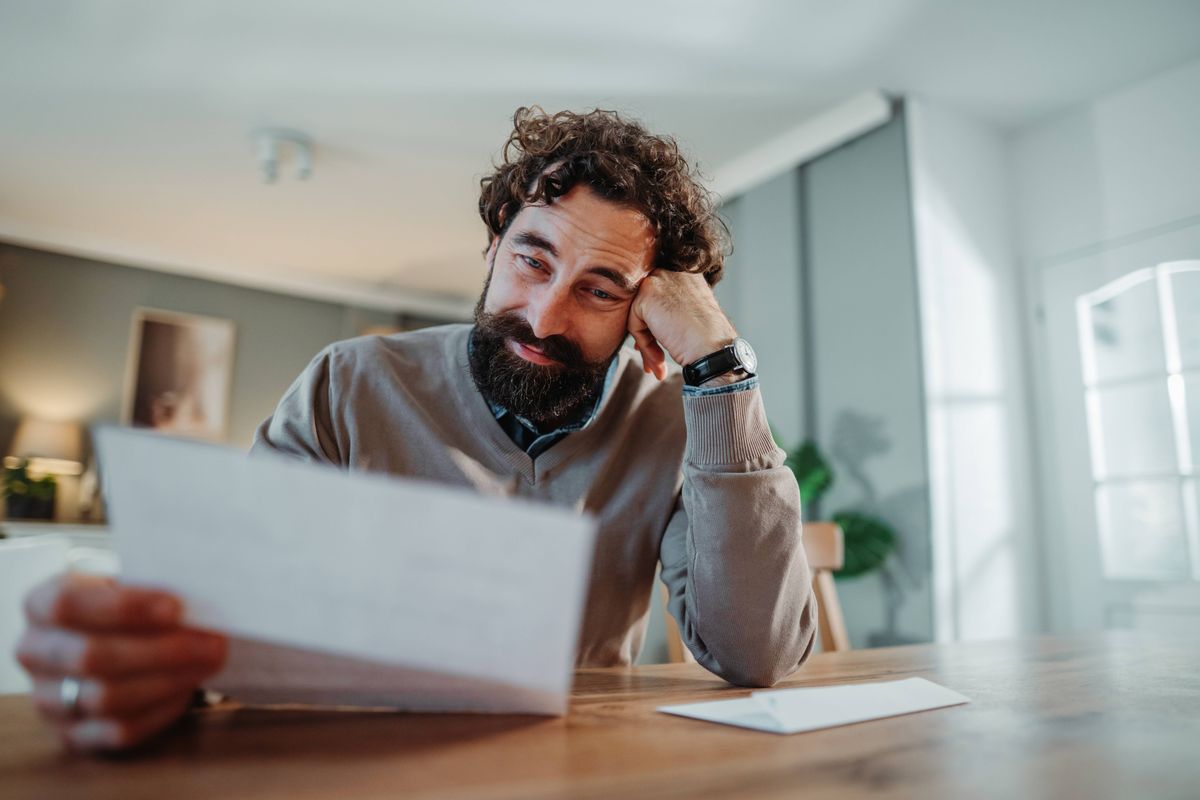 One man feeling overwhelmed while managing personal finances and paperwork at a table