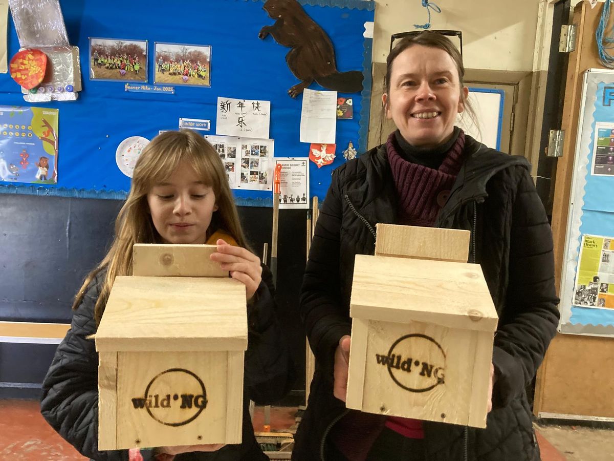Rachel and Eva are holding the bat boxes they built for Wild.NG's project