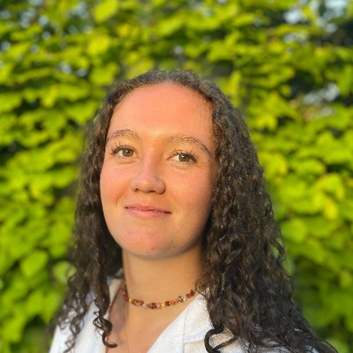 An image of a young woman with dark curly hair.