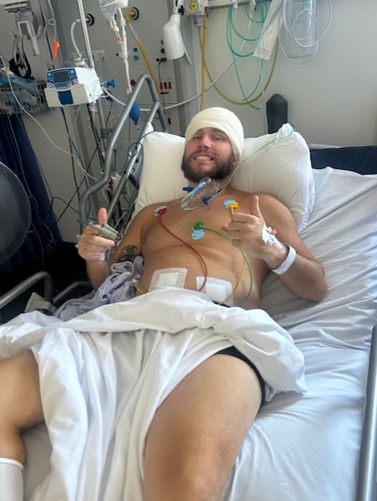A man in a hospital bed with thumbs up