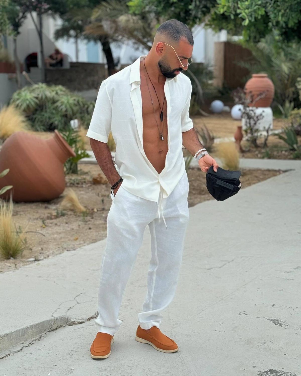 Mohamed Salah posing for a photo with an open shirt and white trousers