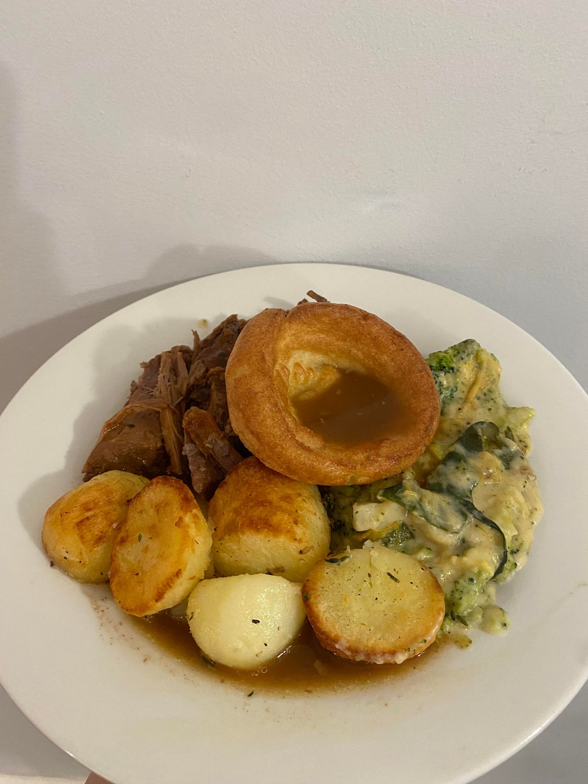 A plate of beef, potatoes, Yorkshire puddings and cheesy greens 