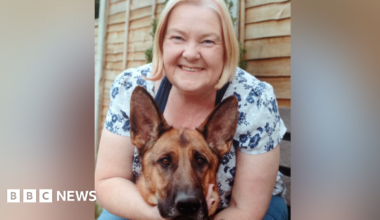 A blonde woman with her arms around a German Shepherd dog.