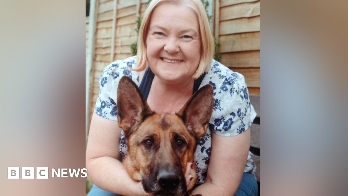 A blonde woman with her arms around a German Shepherd dog.