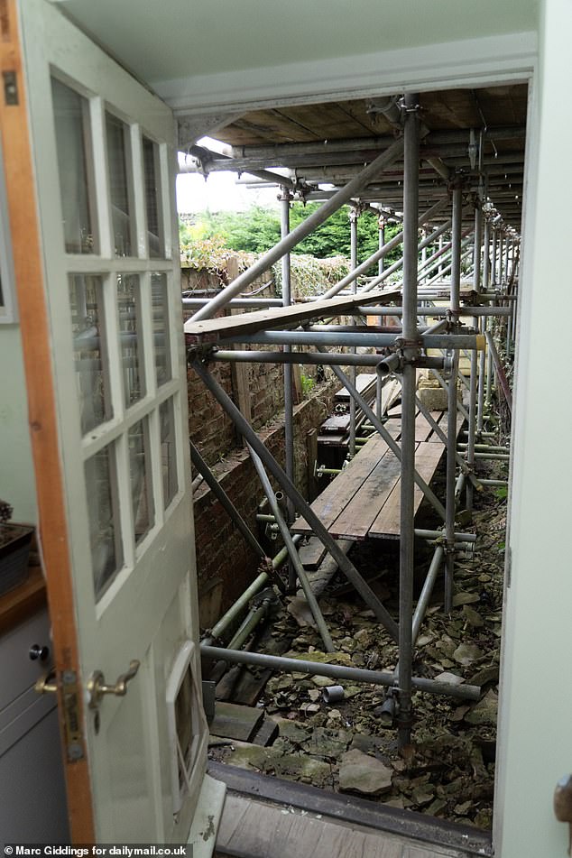 Pictured: The scaffolding, which is visible as soon as Mr Ewart-James opens his back door