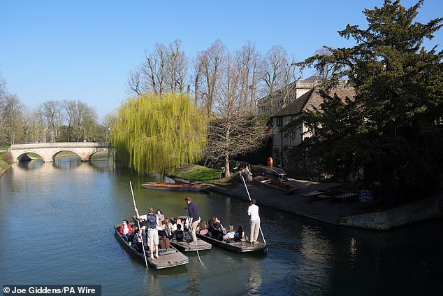 People enjoy the sunshine as they punt along the River Cam in Cambridge on a warm day today