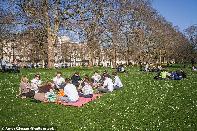 People enjoy the sunshine and warm weather at St James's Park in London this afternoon