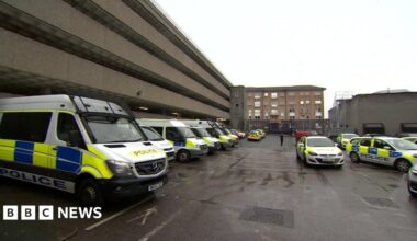 A view of the Charles Cross police station's car park. There are parked police vehicles. To the left is the multi-storey carpark.