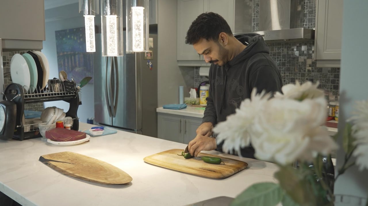 A man standing alone cuts vegetables in a kitchen