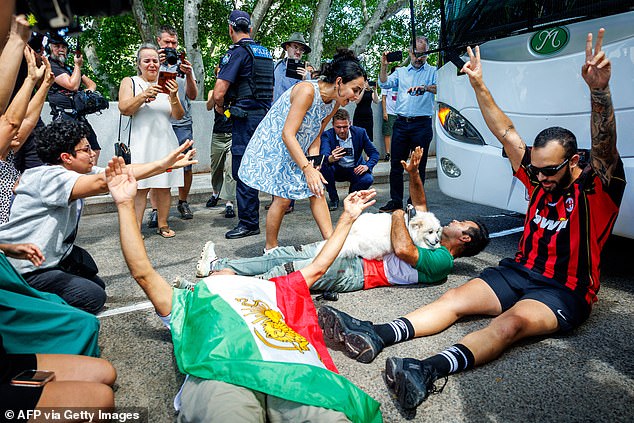 TOPSHOT - Members of the Iranian community in Australia block the path of a departing bus transporting members of the Iranian Women's Asia Cup football team to the airport, outside the Royal Pines Resort on the Gold Coast on March 10, 2026. Five players in Iran's visiting women's football team have taken asylum in Australia over fears of persecution at home for not singing the national anthem before a match, the government said on March 10. (Photo by Patrick HAMILTON / AFP via Getty Images)