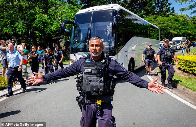 TOPSHOT - Police officers clear the road for a departing bus transporting members of the Iranian Women's Asia Cup football team to the airport, after members of the Iranian community in Australia attempted to block its path, outside the Royal Pines Resort on the Gold Coast on March 10, 2026. Five players from Iran's visting women's football team claimed asylum in Australia on March 10, seeking protection after they were branded "traitors" at home for refusing to sing the national anthem. (Photo by Patrick HAMILTON / AFP via Getty Images)