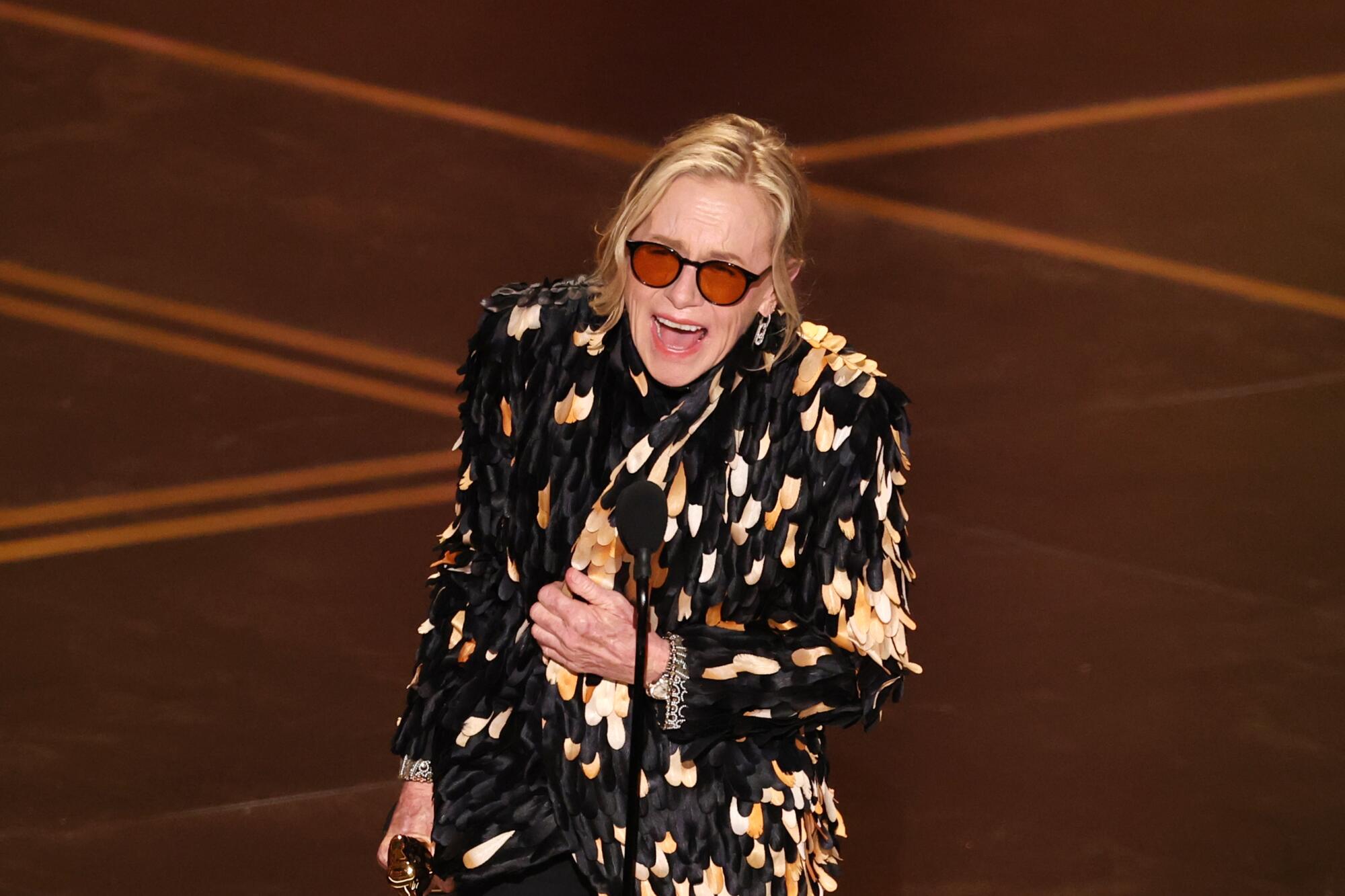 Amy Madigan holds her Oscar on stage.