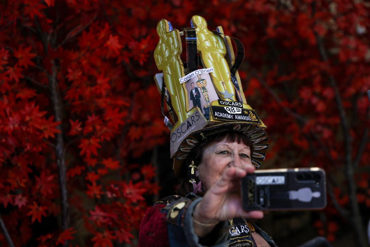 A woman wearing a hat with oscar cutouts takes a selfie