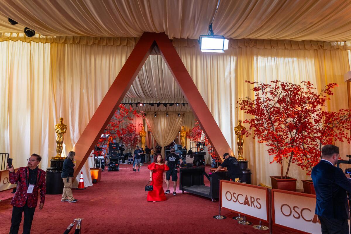 Workers and media members make preparations on the red carpet for the Oscars