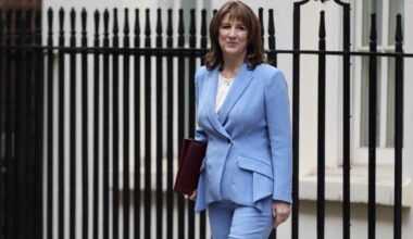 Rachel Reeves delivering spring statement at podium with financial charts in background, addressing economic policies.