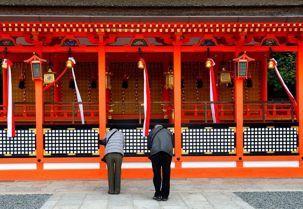 People bowing at shrine in Fushimi Ward, Kyoto, Japan 