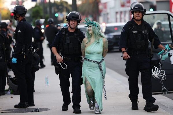 Police arrest a protester dressed as the Statue of Liberty, in downtown Los Angeles after the "No Kings" rally Saturday, March 28, 2026. (AP Photo/Jill Connelly)