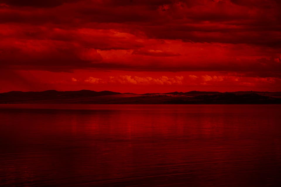The surface and the island of red water scenery. Sky with clouds. Bloody sunset background with copy space for design.