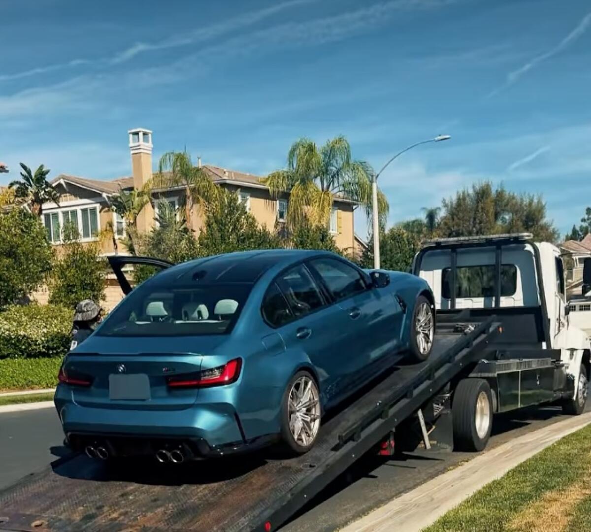 A blue vehicle on a flatbed tow truck