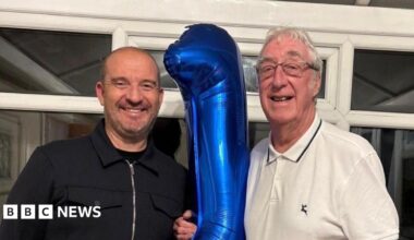 Five members of the families of organ donors line up along the ceramic mural to smile for a photograph.