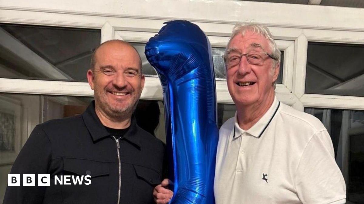 Five members of the families of organ donors line up along the ceramic mural to smile for a photograph.