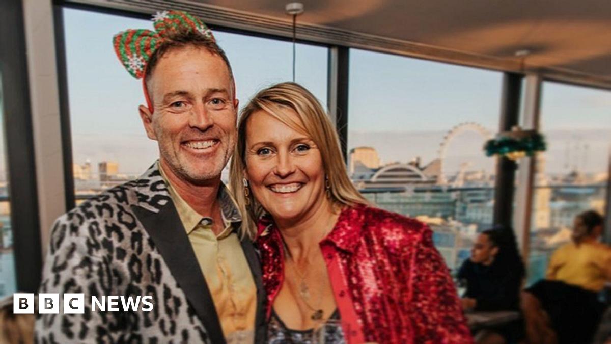 A middle-aged couple are in fancy dress at a party. They look happy.