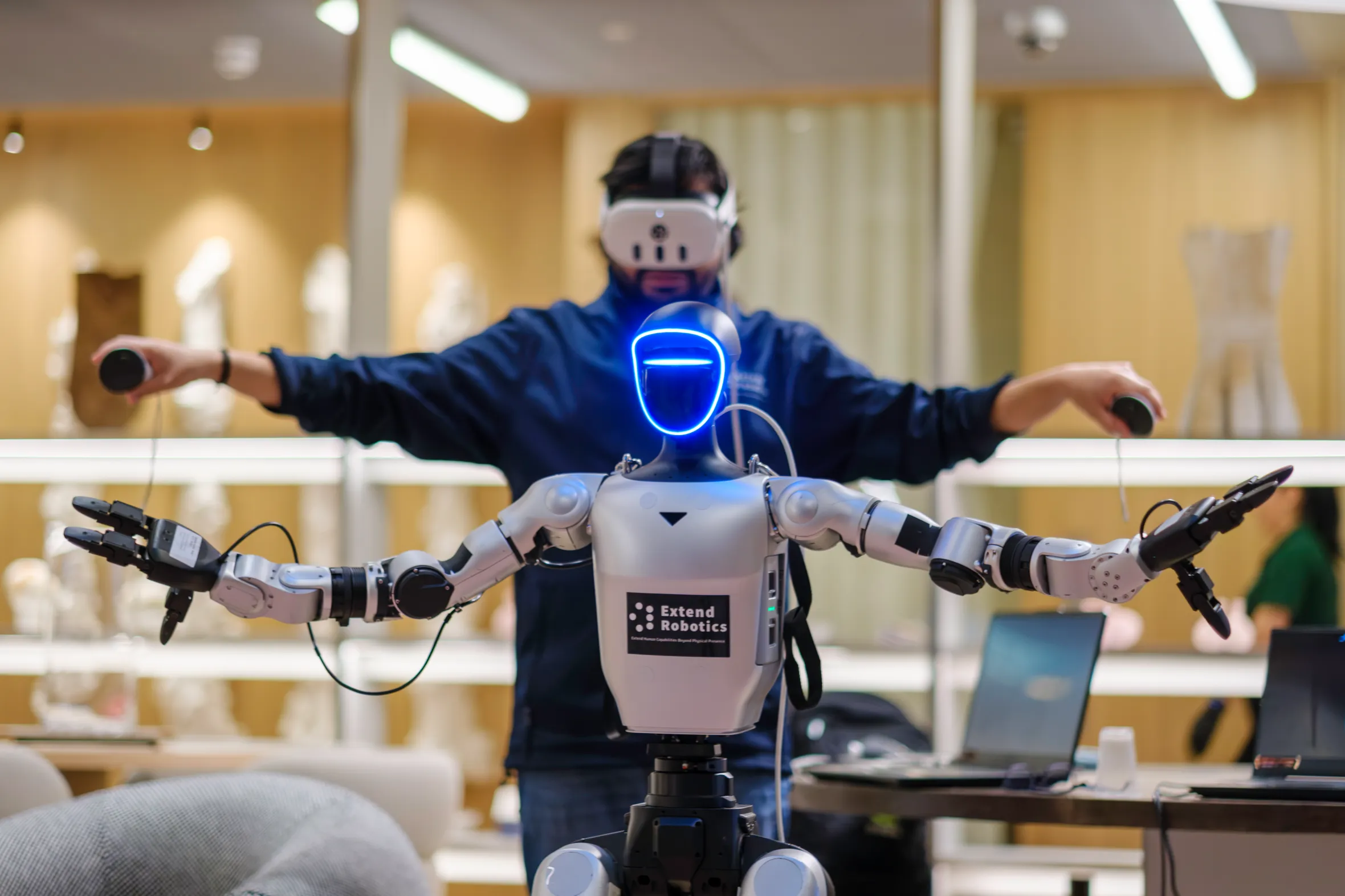 A person in a VR headset controls a robot by spreading their arms, mimicking the robot’s pose.