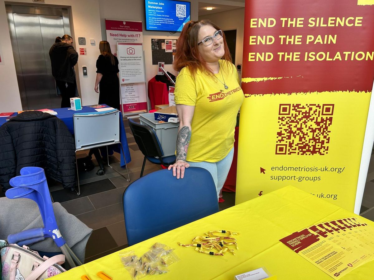 Jenni Johnson pictured next to an Endometriosis UK banner with her crutches next to her