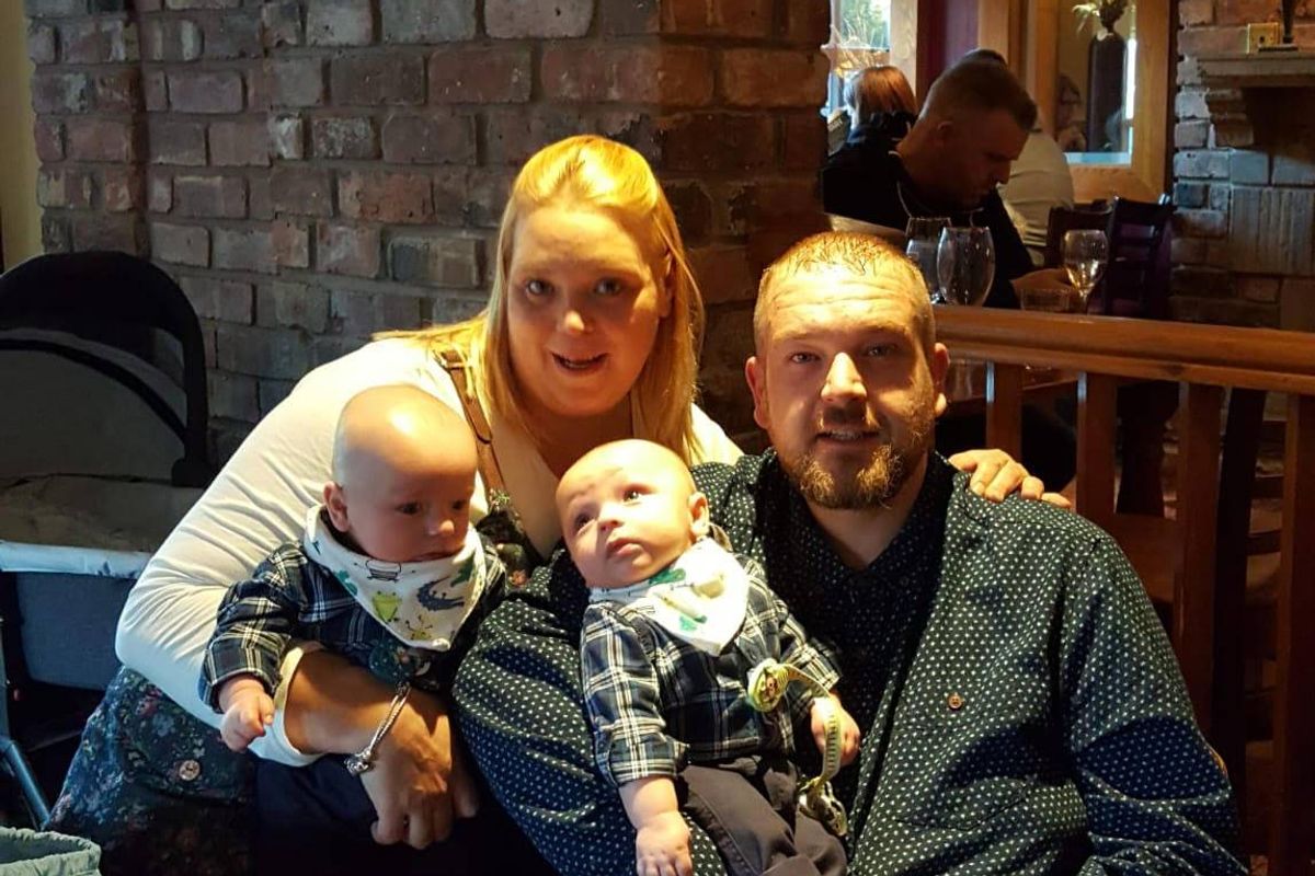 Smiling parents with their twin baby sons at a restaurant table
