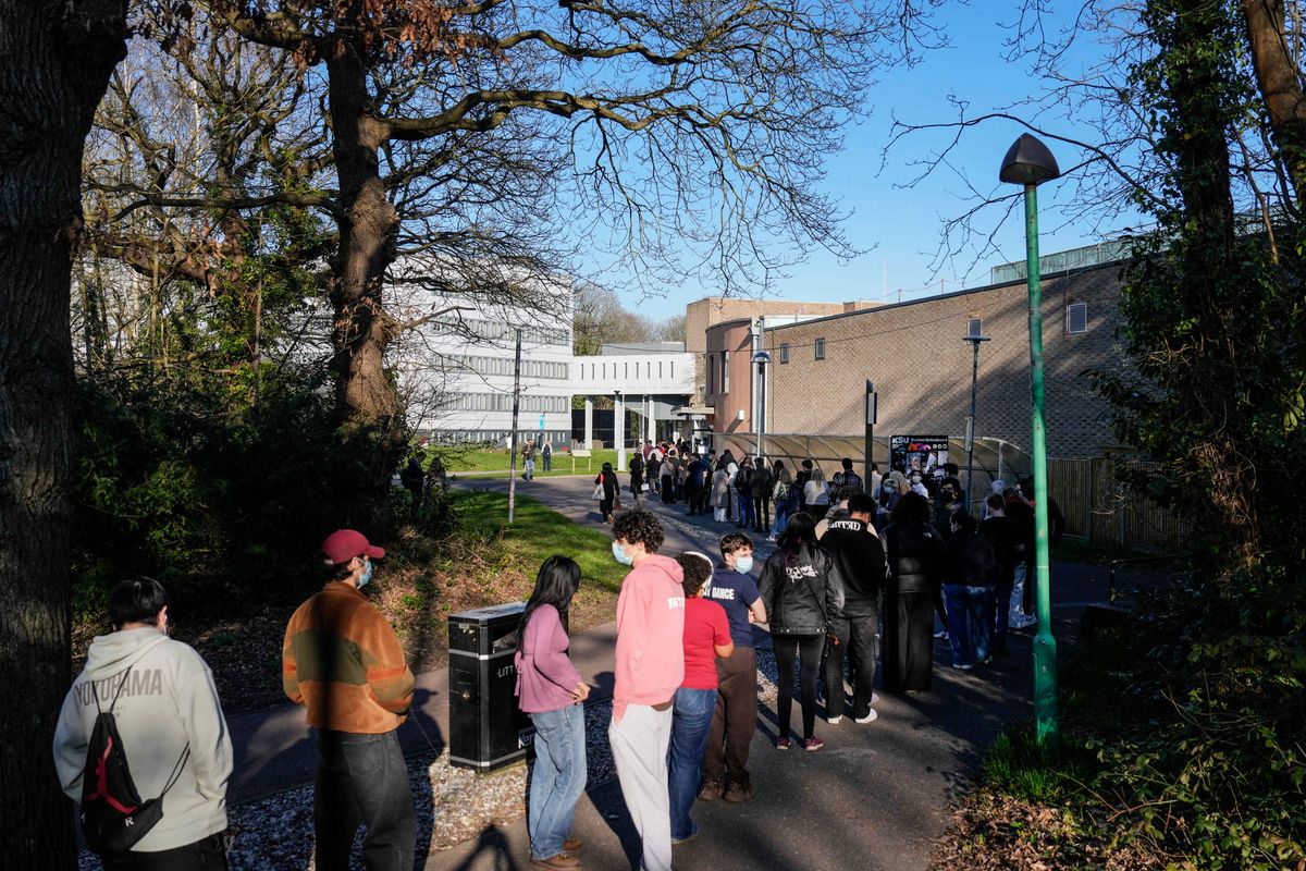 Students wearing face masks queue up to get vaccinated at the University of Kent in Canterbury, south-east England on March 18, 2026, following an outbreak of meningitis. Hundreds of masked-up students queued on March 18 to get vaccinated at the UK university campus at the heart of a deadly meningitis outbreak, as the number of cases rose to 20. 