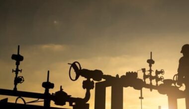 oil worker turning the valve on a pipeline