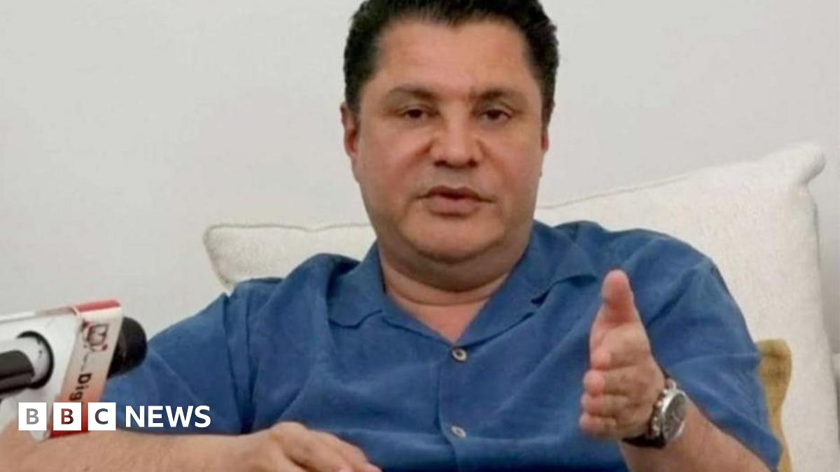 Rostam Aziz, wearing a blue shirt, speaking at a press conference