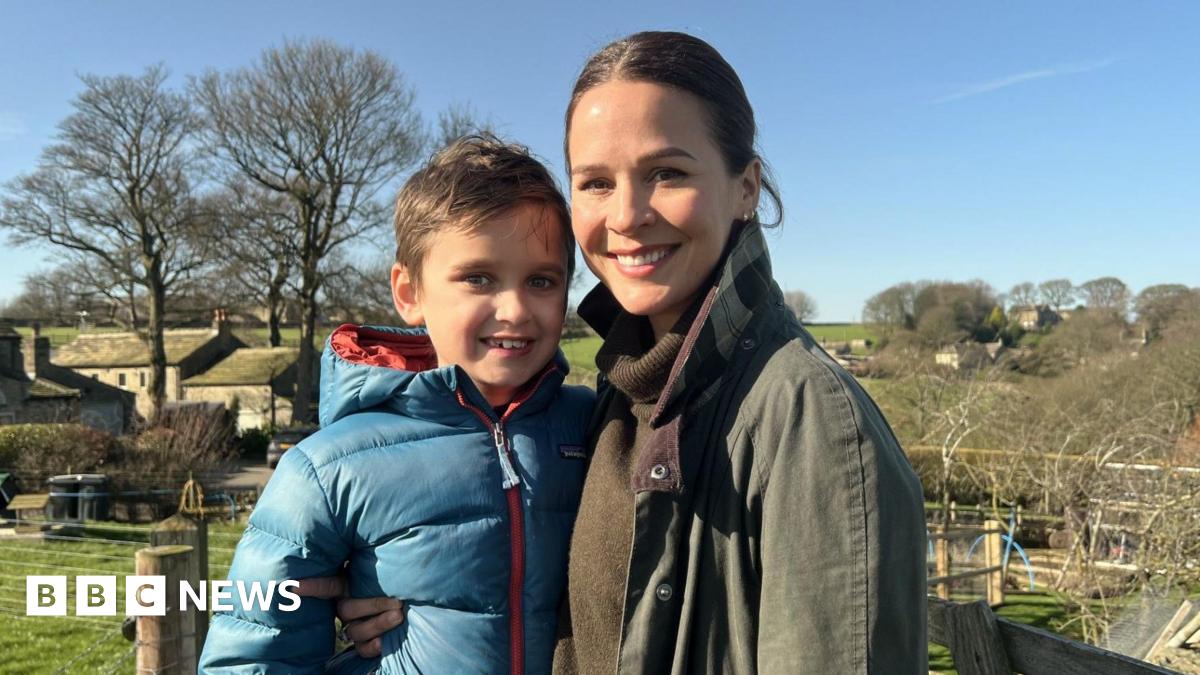 Freddie and his mum, Lauren, stand in the sunshine in fields near their home in Huddersfield