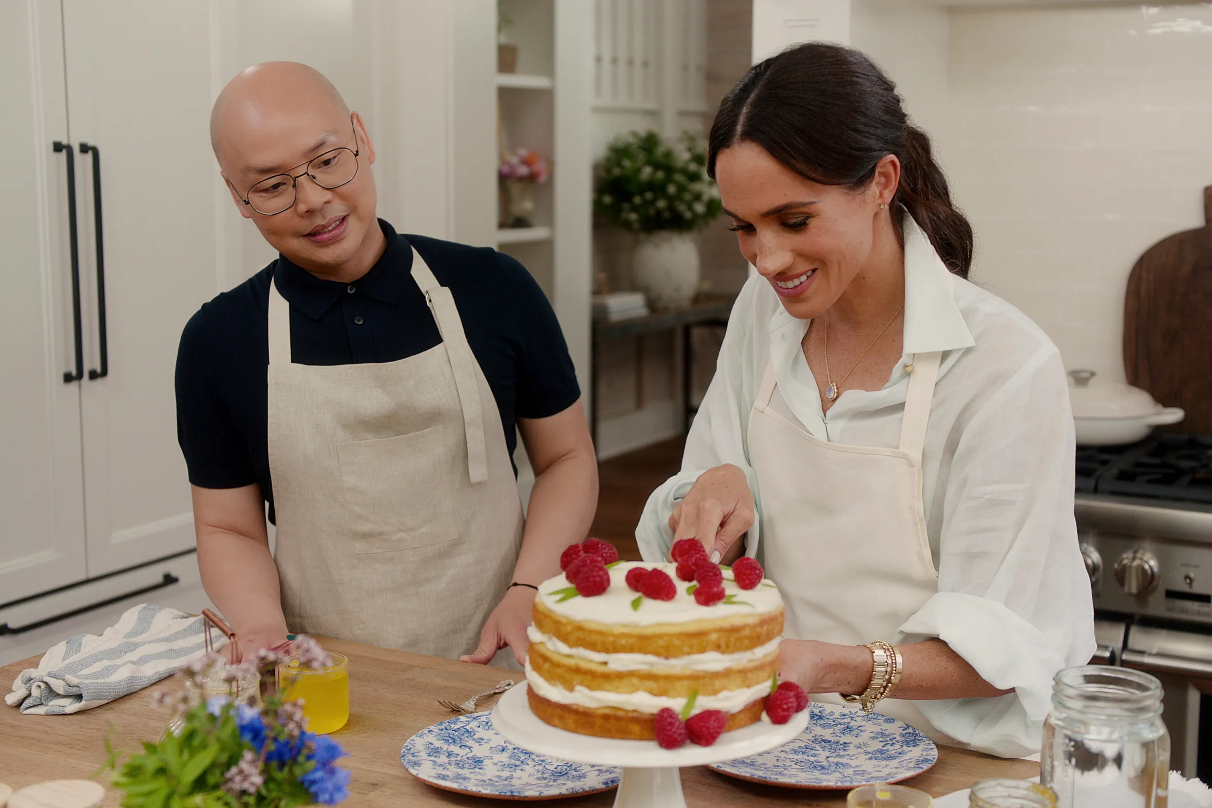 Daniel Martin and Meghan, Duchess of Sussex, decorating a cake with raspberries.