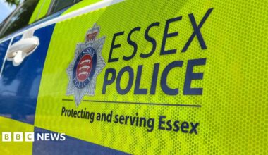 Left side of a police car with blue and yellow logo and writing saying Police - Protecting and serving Essex.