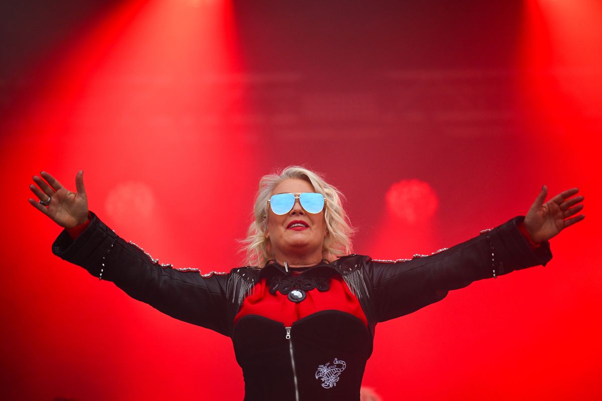 kim wilde on stage with huge mirrored sunglasses and red background