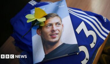 Flowers and football tops and scarves on the ground, surrounding a photograph of a young man, on the front of a magazine entitled "Bluebird".