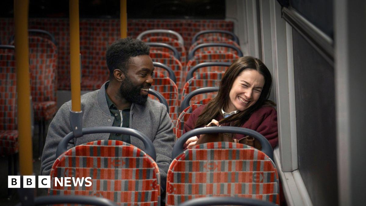 Paapa Essiedu and Siobhán Cullen sitting on the bus and laughing