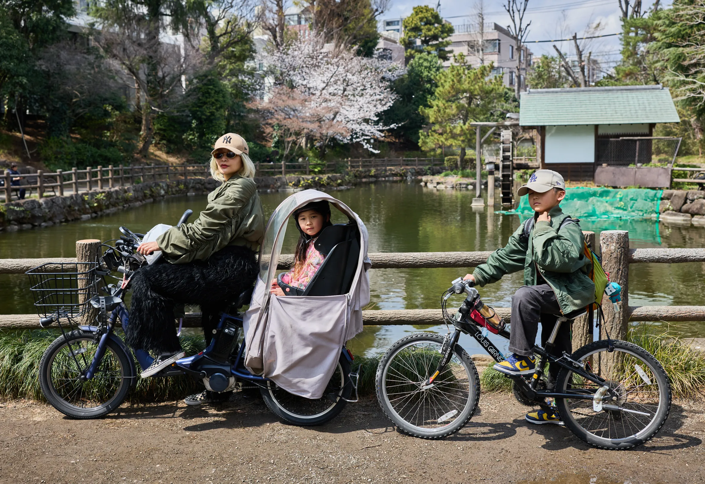 A Japanese family on bicycles beside a lake.