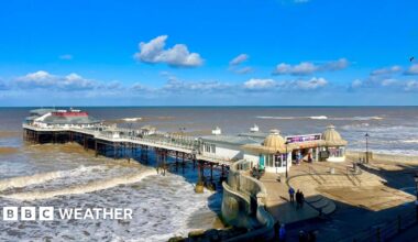 photo of Cromer pier with lots of sunny spells above and with choppy waves beneath