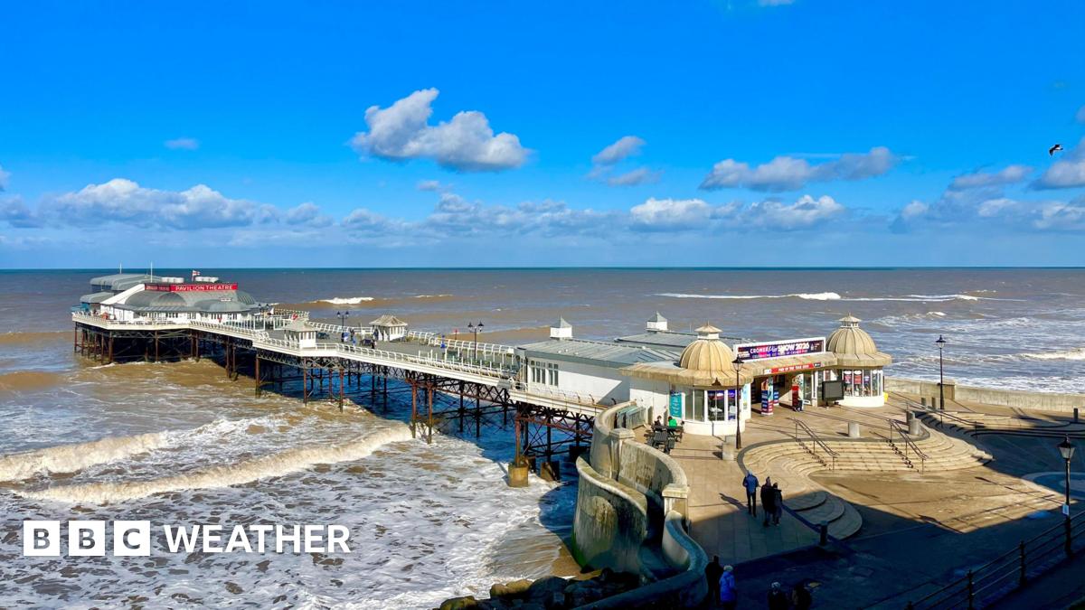 photo of Cromer pier with lots of sunny spells above and with choppy waves beneath