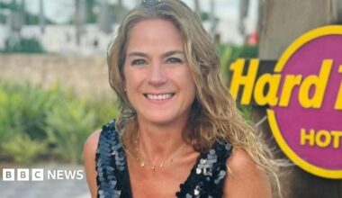 A woman in a black sequinned top on holiday against a Hard Rock sign