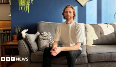Male sitting on sofa wearing T shirt and dark trousers