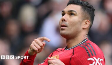 Manchester United midfielder Casemiro points to the club badge on his red shirt