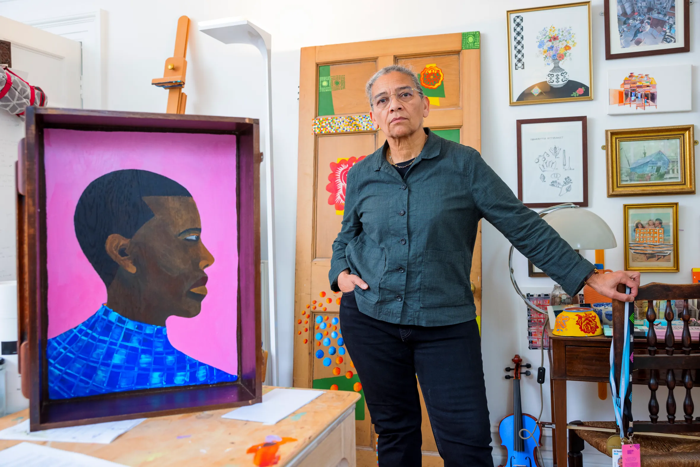 Lubaina Himid in her studio, standing next to a painting of a man.