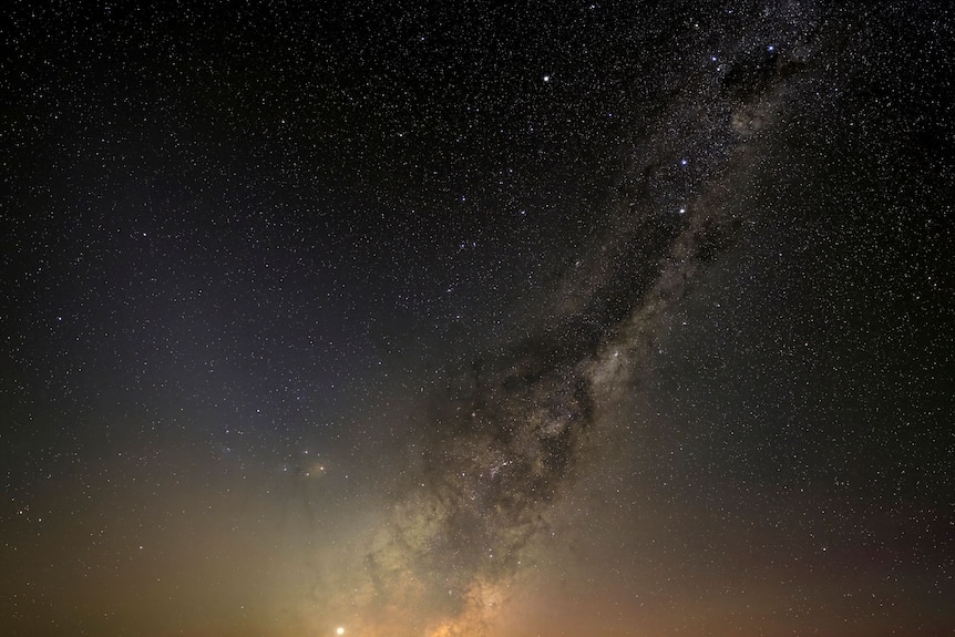 The Milky Way rising in the night sky with a dry slat lake on the ground below.