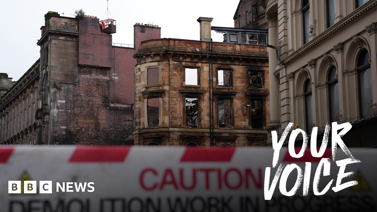 Shell of a fire damaged Victorian building. A red and white barrier warning that demolition is in progress is in the foreground.