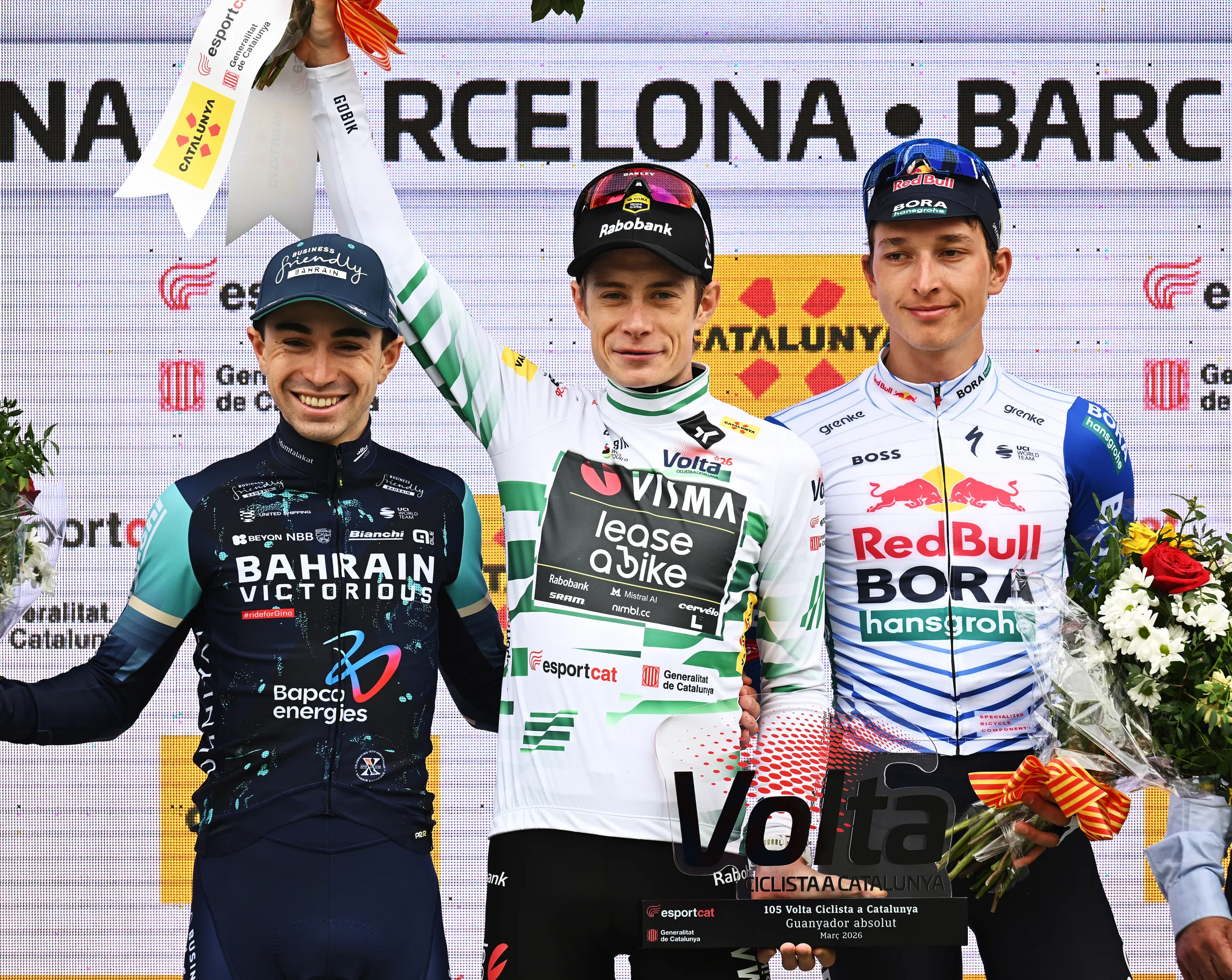 Jonas Vingegaard, center, in the green leader's jersey, celebrates his victory at the 105th Volta a Catalunya 2026, flanked by Lenny Martinez, left, and Florian Lipowitz, right.
